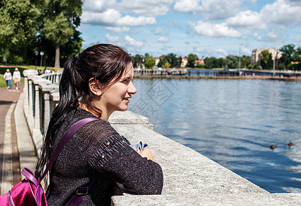女孩看着城市公园的湖边图片