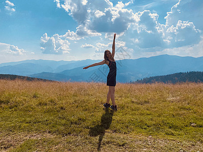 快乐的年轻女孩跳上草地自由乐趣喜悦天空场地活力绿色幸福蓝色跳跃图片