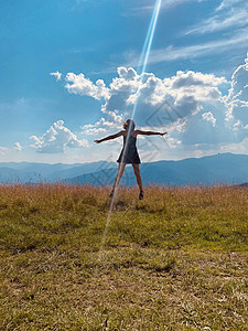 快乐的年轻女孩跳上草地场地天空乐趣幸福绿色活力喜悦自由跳跃蓝色图片