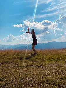 快乐的年轻女孩跳上草地天空自由跳跃活力绿色蓝色幸福乐趣场地喜悦图片