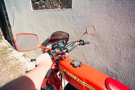 一位男子在阳光明媚的白天持有一辆古老红色红色摩托车图片