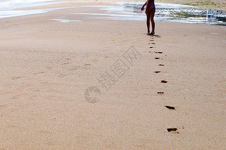 一个年轻女孩的脚赤脚走在潮湿的海滩上 在沙子上留下脚印自由孤独青春期海浪娱乐孩子旅行赤脚海洋休息图片