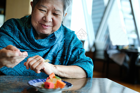 年长的亚洲老年老年妇女在餐厅吃水果图片