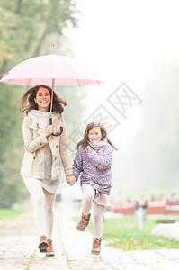 带着雨伞的母亲和女儿在公园散步图片