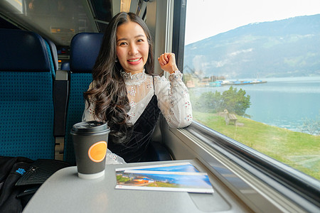 年轻女孩坐在火车上时 四处看望着景色运输窗户旅行成人假期播客阅读商业快乐公共汽车图片