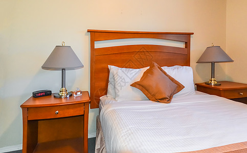 卧室内部有收音机手表 香水桶和床边桌子上的灯具商业旅游枕头旅馆公寓床罩财产汽车软垫酒店图片