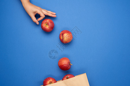 红色纸袋棕色纸袋和成熟的红苹果 女性手推苹果背景