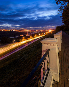 夜间在城市中行驶的汽车灯光模糊 河上和公路上有桥 公园从高处看一眼 前墙有栅栏基础设施场景运动小路市中心正方形街道景观运输天际图片