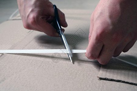 一个人用剪刀砍了一块纸板来组装家具图片