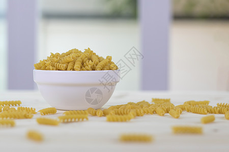 白杯中的fusilli 放在木制桌子上的白色杯子上图片