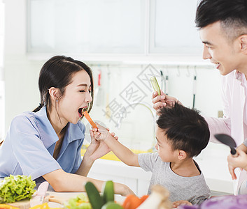 快乐的小男孩喂妈妈 在厨房吃一块胡萝卜图片