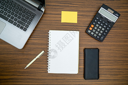 办公桌工作环境 棕色条纹斑马木设计桌面上的记事本 便签 笔杆 计算器和膝上型电脑 在 Covid19 期间在家工作时必须有物品活图片