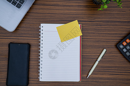 彩色褐色工作桌 有注纸 移动电话 笔 计算器以及一台膝上型电脑和桌上设备笔记纸活页夹软垫自由职业地点桌子木头金融小样铅笔图片