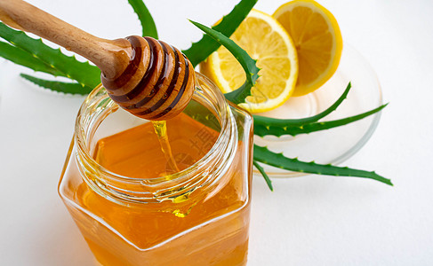 芦荟蜂蜜用于加强白色背景的免疫系统的有用成分 用罐子 柠檬和 aloe Vera进行蜂蜜芦荟背景