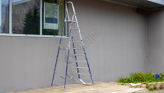 一个施工梯子站在灰色建筑的外墙旁边 门外 一步梯式平台 (笑声)图片