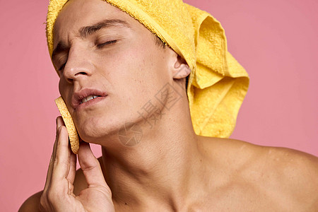 头上戴毛巾的男子和手掌上印有黄色海绵的人 将脸皮清洗干净奶油微笑护理男人身体头发卫生剃须治疗皮肤图片