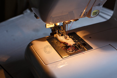 特写缝纫机 灯光照明 工作场所裁缝 缝纫业工厂材料宏观棉布生产服装工具爱好家庭金属图片