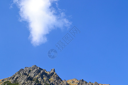 岩石顶端与蓝天相对的蓝色天空 与云层相连图片