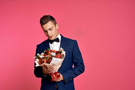 浪漫的男人 花束束花 和领结 在粉红背景的草原风景上玫瑰生日男朋友展示惊喜成人男性花朵周年纪念日图片