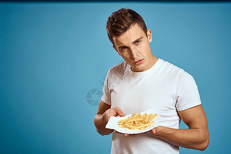 男人用硬纸板炸薯条卡路里快餐蓝色背景青少年模型裁剪视图芝士午餐胡子男性营养脂肪汉堡工人成人饮食图片