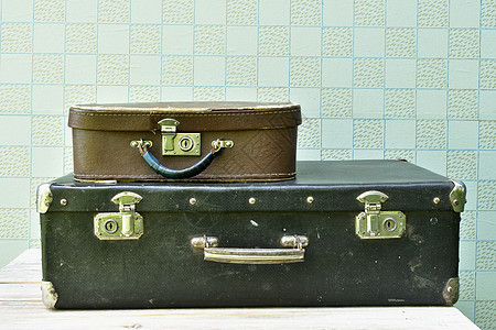 两个旧的手提箱 黑色大件和小棕褐色 在复古间磨损合金桌子金属墙纸破烂图片