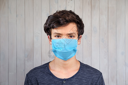 戴着医用面罩的年轻人看着相机 冠状病毒 covid-19 爆发 15 岁男孩戴着面具的棕色眼睛 病毒 细菌 流行病爆发 公共卫生图片