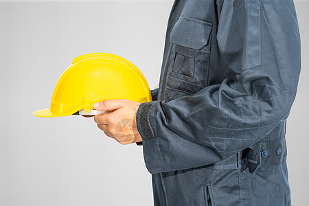 站在蓝色封面内站着的贴近工作员工作服员工手臂头盔职业塑料工作工作室制造业制服背景图片