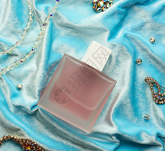 粉红色全瓶 有霜冻的玻璃香水 躺在蓝色背面上石头化妆品香水厂瓶子液体女性空白奢华商品胸针图片