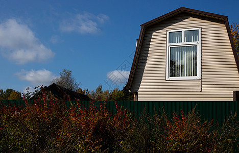 村里的小型乡村房屋 在围栏附近美丽的秋天灌丛图片