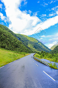 美丽的潮湿道路 山地云雾般的挪威天空旅游晴天蓝色山脉国家农村森林旅行维肯明信片图片