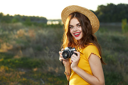 开心的女摄影师笑脸帽子在大自然中行走 新鲜空气相机女性女士公园爱好喜悦照片快乐成人娱乐图片