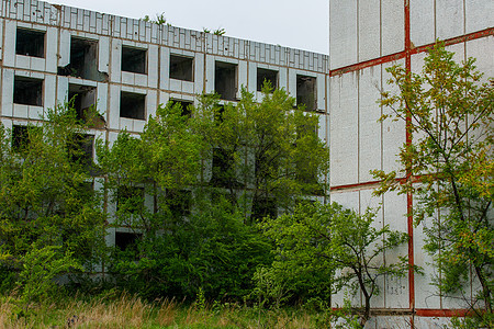 一栋废弃的多层建筑矗立在绿地中央 没有窗户的多层建筑天花板蓝色摩天大楼地面房子光圈多层脚手架房间建筑图片