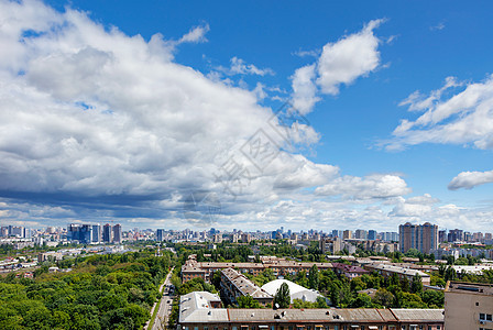 一个城市景观 在城市的一个老住宅区有一个绿色公园 在明亮的蓝天和厚厚的云层的映衬下 地平线上有新建筑图片