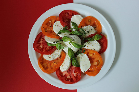 白色和红色的白红背景上 一份配西红柿和奶酪的盘子图片