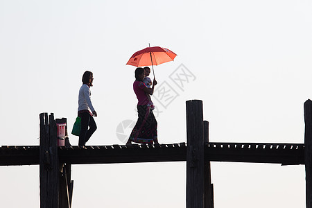 缅甸曼德勒(Mandallay)桥上的当地妇女 带儿女和红雨伞图片