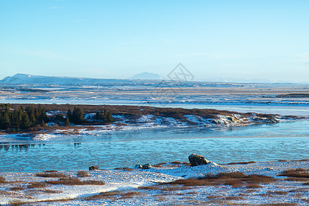 冰岛平原的河流 河岸上满是积雪 冬季风景 空旷的空间冰川流动太阳旅行悬崖天空溪流日落场景地质学图片