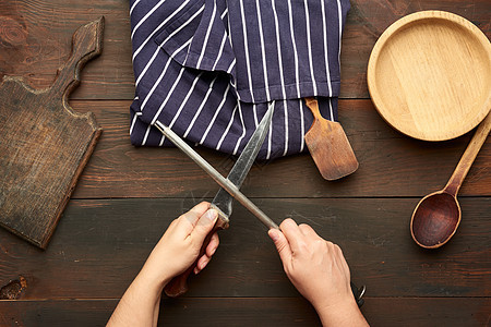 女用手握着厨房刀和手柄的磨刀木材烹饪食物工具工作桌子木头砧板木板棕色图片