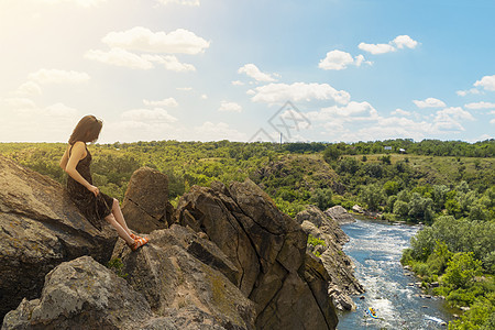 一位年轻女性坐在一块岩石上 看着南虫河的景色 乌克兰虫子警卫国家自然公园 股市照片森林蓝色游客女孩风景石头公园自由旅游闲暇图片