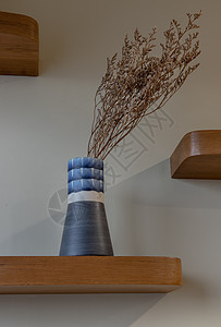 鲜花在美丽的陶瓷蓝色花瓶中 站在木头上架子潮人风格家居制品桌子陶器客厅艺术装饰图片