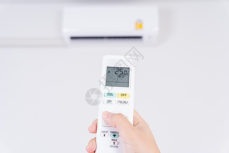 人手正在使用空调的白色遥控器打开或调节室内空调的温度控制展示房子技术气候力量呼吸机冷却器房间按钮图片