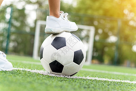一个穿着白运动鞋的男孩脚踏上足球球惩罚运动草地训练闲暇场地游戏操场娱乐天空图片
