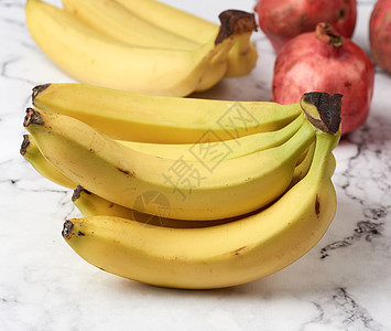 白大理石桌上的黄香蕉和成熟的红石榴皮肤水果营养工作室桌子饮食食物美食热带石榴图片