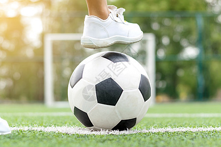 一个穿着白运动鞋的男孩脚踏上足球球竞赛乐趣游戏草地娱乐惩罚活动管道体育场天空图片