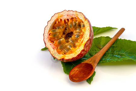 Maracuja在小玻璃容器里用木勺和白底的叶子将水果切成半截整片 果实黄色 果汁和种子木头玻璃茶匙勺子饮食甜点食物热情热带宏观图片