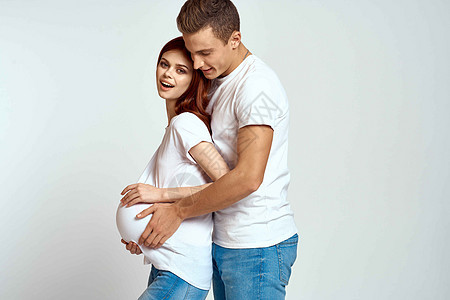 一个孕妇和一个年轻人在浅色背景下等待婴儿的情绪家庭爱母亲夫妻女性孩子男性男人家庭母性生活幸福图片