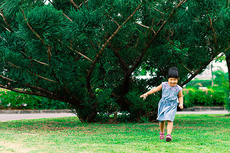 穿着裙子的快乐小女孩 在公园里跑来跑去图片