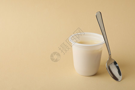 塑料酸奶杯 米色背景上勺子图片