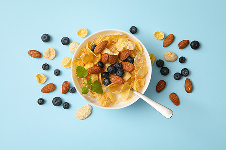 蓝色背景的带有穆埃斯利 杏仁 薄粉和蓝莓的碗烹饪饮食活力粮食浆果坚果谷物盘子营养覆盆子图片