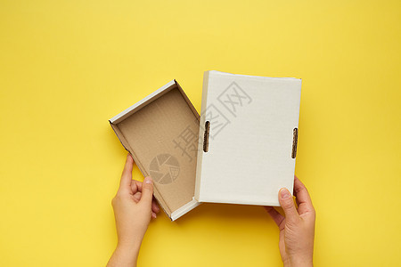 两只雌性手拿着一张黄色背面的空纸盒图片