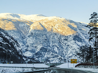 日出时驾车穿过挪威的山脉和森林旅行雪景公路景观极夜农村金光街道速度树木图片